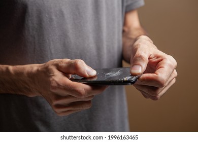 Man Holding Broken Phone On Brown Background