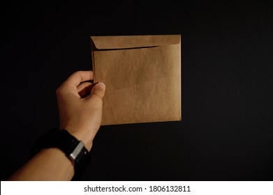 Man Holding Brown Envelope On Black Background