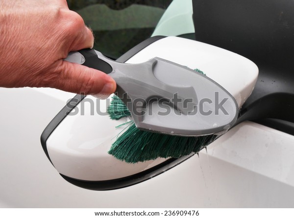 Man holding brush to\
clean car mirror