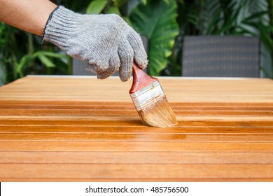 A man holding brush and painting on the wooden table
