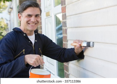 Man Holding Brush And Tin Painting Outside Of House