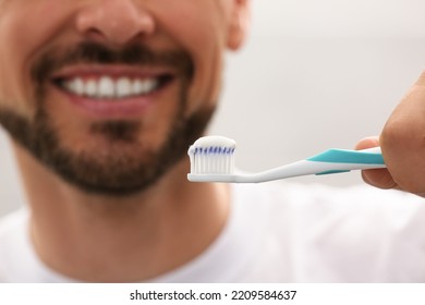 Man Holding Brush With Toothpaste On Grey Background, Closeup