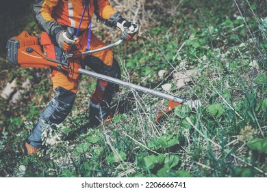 Man holding a brushcutter cut grass and brush. Lumberjack at work wears orange personal protective equipment. Gardener working outdoor in the forest. Security, occupation, forestry, worker, concept - Powered by Shutterstock