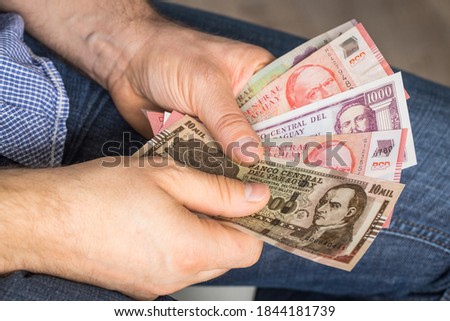 a man holding a bundle of Paraguayan currency in his hands, Guaranies. Money of any value