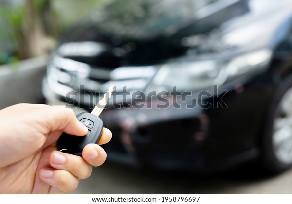 A\
man holding a car key in front of a car at a\
showroom