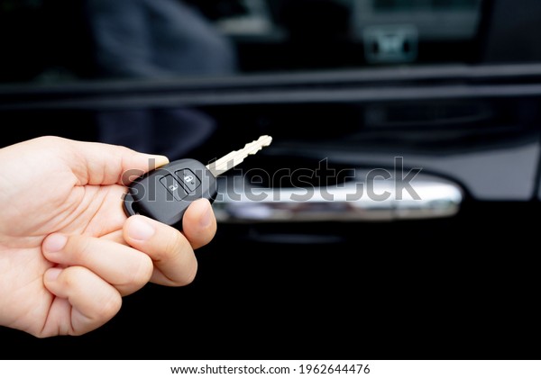 A
man holding a car key in front of a car at a
showroom