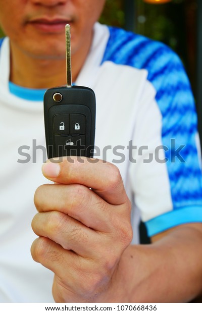 A man holding a car\
key in his hand.