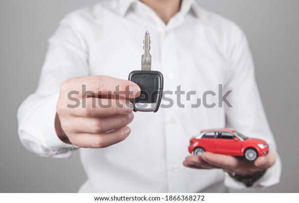 Man holding car key\
with car in office.