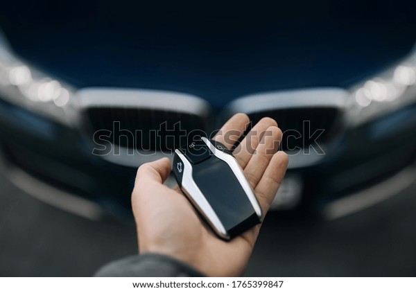 Man is holding\
car keys in the front of\
car