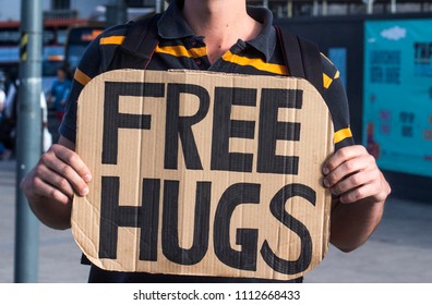 Man Holding A Cardboard Sign With Free Hugs Written On It