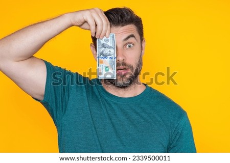 Man holding cash money in dollar banknotes on isolated yellow background. Studio portrait of businessman with bunch of dollar banknotes. Dollar money concept. Career wealth business. Cash dollar.