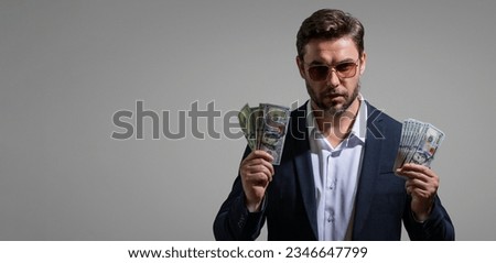 Man holding cash money in dollar banknotes on isolated gray background. Studio portrait of businessman with bunch of dollar banknotes. Dollar money concept. Career wealth business. Cash dollar banner.