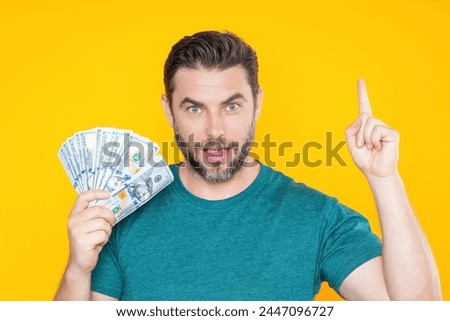 Man holding cash money in dollar banknotes on isolated yellow background. Studio portrait of business man with bunch of dollar banknotes. Dollar money concept. Career wealth business. Cash dollar.