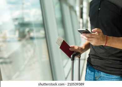 Man Holding Cell Phone, Passports And Boarding Passport At Airport Waiting The Flight