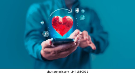 A man holding a cell phone with a red heart shape on it. The heart is surrounded by other icons such as a medical, a heartbeat, a medicine and a healthcare. Concept of healthcare and insurance - Powered by Shutterstock