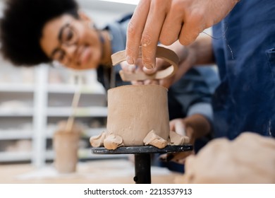 Man holding clay near sculpture and blurred african american teacher in pottery workshop - Powered by Shutterstock