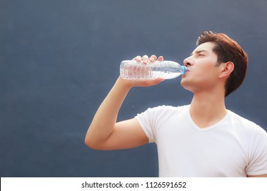 Man Holding Clean Fresh Mineral Water Bottle With Court Background, Drinking Water Outdoor Under Summer Heat. Health Care, Well Being, Thirst Refreshment, Water Balance In Body Is Medicine Concept