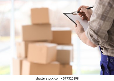 Man holding clipboard on blurred boxes background