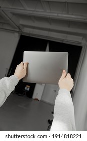 A Man Holding A Closed Laptop Above Him