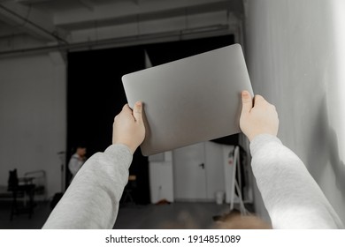 A Man Holding A Closed Laptop Above Him