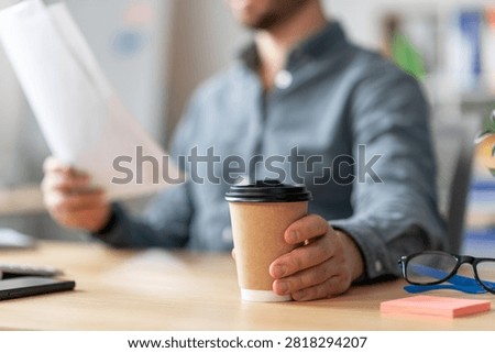 Man Holding Coffee Cup While Reading Documents At Office Desk, Business Concept