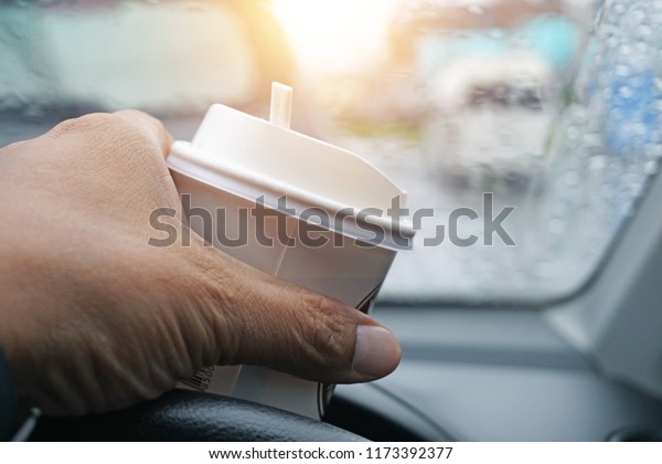 Man holding coffee paper cup in car ,Paper cup coffee of\
hot holding hand in a car in the morning                           \
  