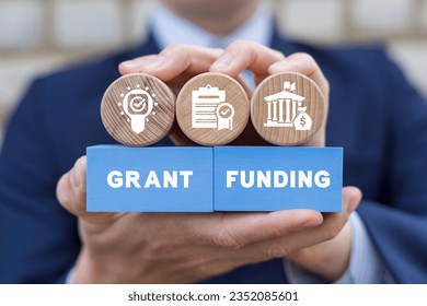 Man holding colorful blocks with icons and inscription: GRANT FUNDING. Concept of grants and funding.