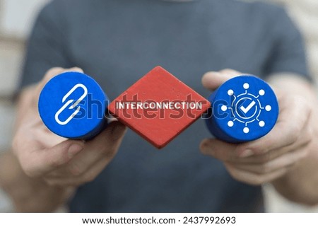 Man holding colorful blocks sees word: INTERCONNECTION. Interconnected digital cyber era technology. Social networking interconnection communication concept. Big data and city interconnection tech.