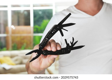 Man holding compact portable multitool indoors, closeup
