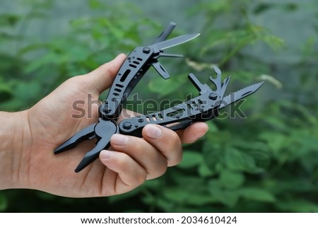 Man holding compact portable multitool outdoors, closeup