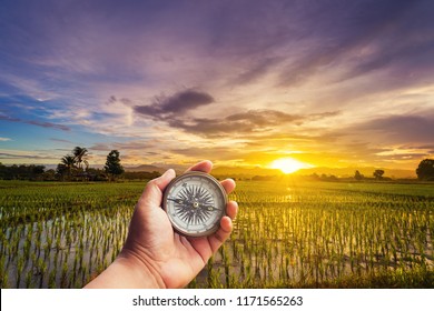 A Man Holding Compass On Hand At Field And Sunset For Navigation Guide.