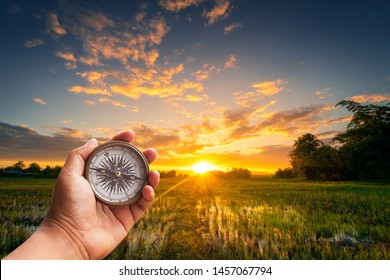 A man holding compass on hand at field and sunset for navigation guide. - Shutterstock ID 1457067794