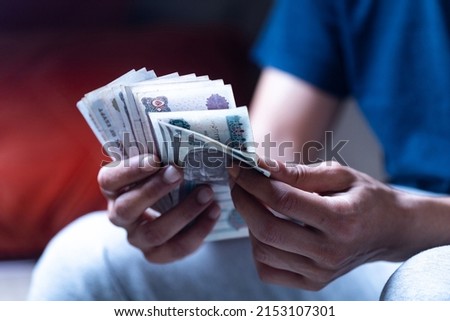 man holding and counting Egyptian currency 