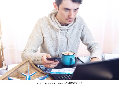 Man holding a credit card and buys plane tickets on the Internet working on the laptop. The concept of travel and transport, buying and booking