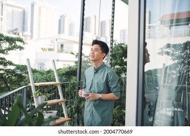 man holding cup of coffee and smiling on balcony - Powered by Shutterstock