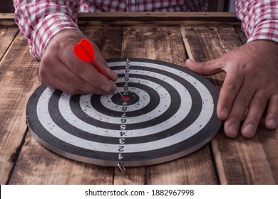 man holding dart arrow hit in target center of dartboard - Shutterstock ID 1882967998