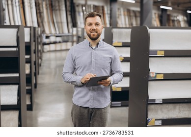 Man holding a digital tablet checking inventory or managing stock in a modern hardware store. Business and technology concept