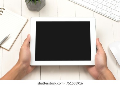 Man Holding Digital Tablet With Copy Space While Sitting At Wooden Desk, Top View