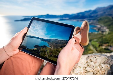 Man holding digital tablet on the mountain top on the sea scape background