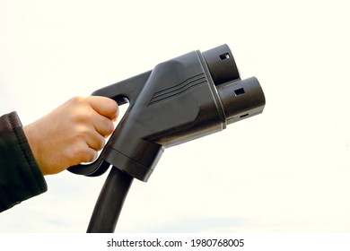 Man Holding A EV Charger Against The Cloudy Sky. Copy Space. EV Charger. Electric Vehicle Charging. Alternative Energy. Modern Technology. High Quality Photo