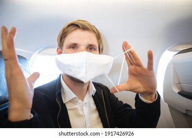 Man Holding FFP2 Face Mask While Sitting Into An Airplane Time To Upgrade Masks As Coronavirus Variants Emerge. Plane Flight Wearing Mask In Cabin Covid-19 Protection Respirator For Public Health. 