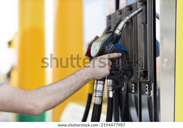 Man\
holding filling gun in his hand at gas\
station.