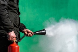 A Man Is Holding A Fire Extinguisher And A Hose With A Bell From Which Carbon Dioxide Escapes.