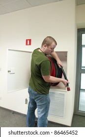 man holding a fire hose in an office building