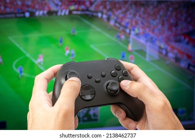 Man holding game controller playing football game.