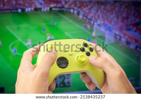 Man holding game controller playing football game.