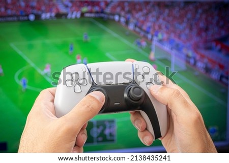 Man holding game controller playing football game.
