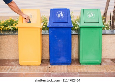 A Man Holding Garbage Into Recycle Bin.Row Of Different Waste Bin At The Public Park.