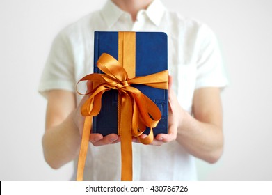 the man holding a gift - blue book with gold bow