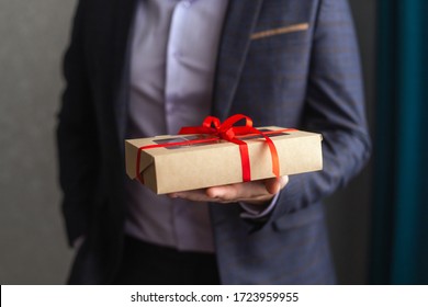 Man Holding A Gift Box With A Red Bow On One Hand